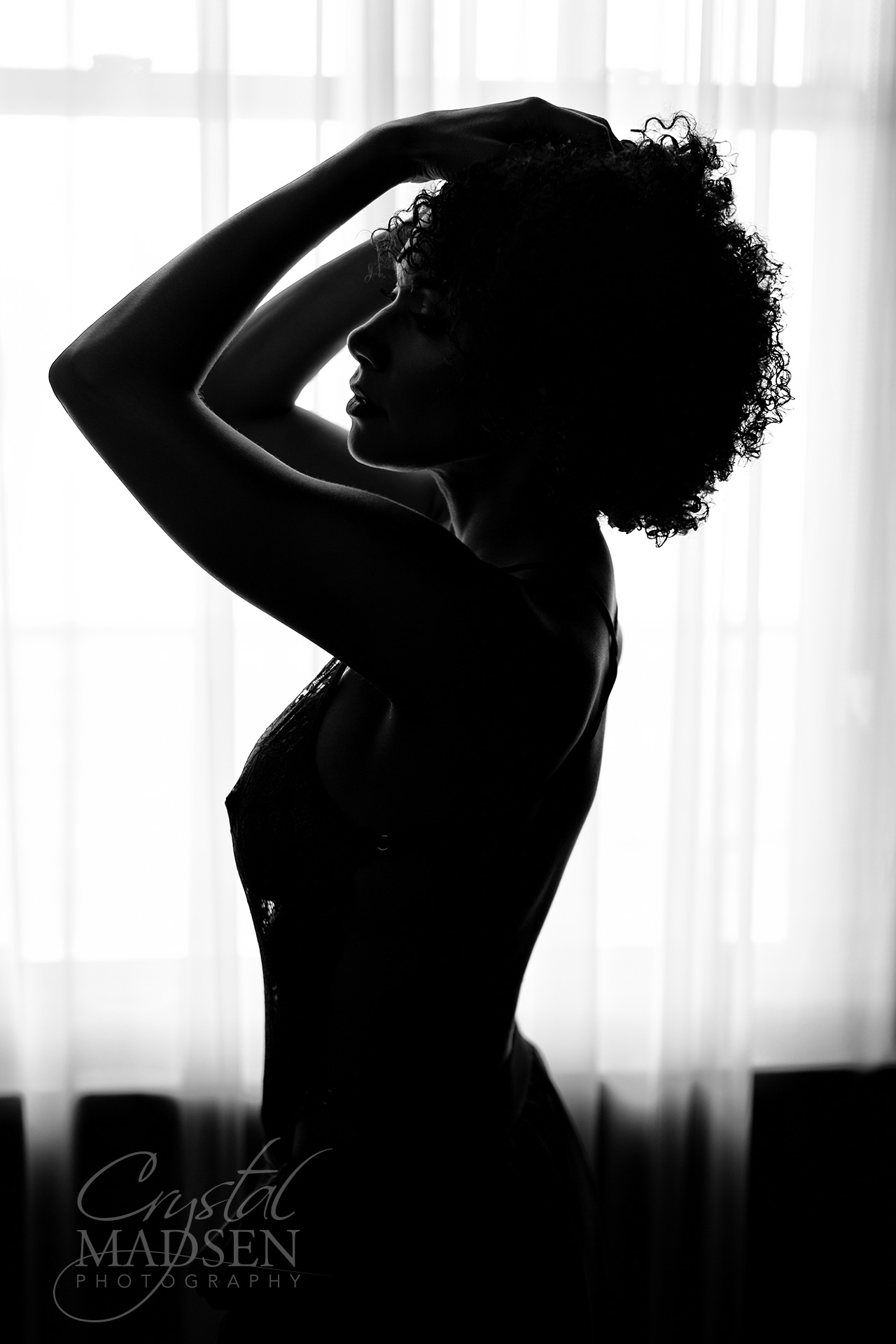 a black woman posing for a boudoir photo in front of a window