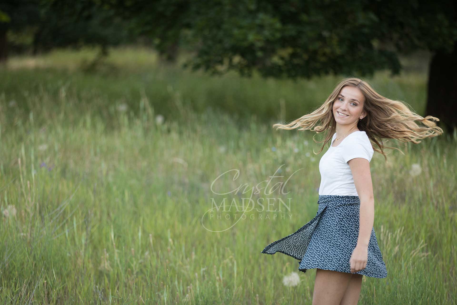 playful senior girl spinning in green field